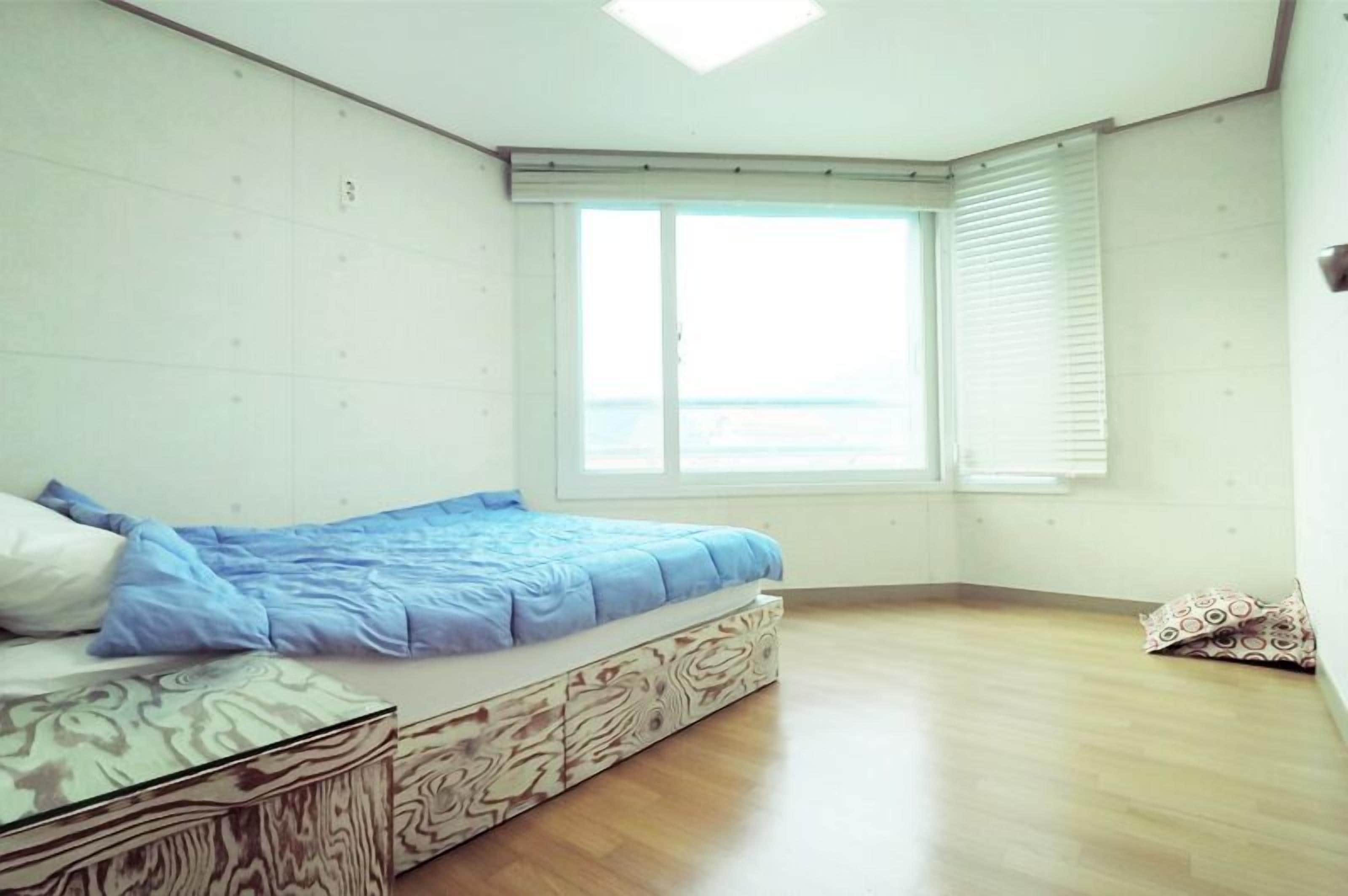 Un dormitorio con cama, ventana y suelo de madera.