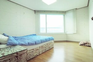 Un dormitorio con cama, ventana y suelo de madera.