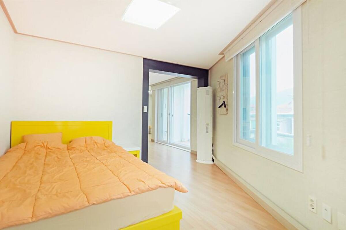 Une chambre à coucher avec un lit, une fenêtre et une porte donnant sur une autre pièce.