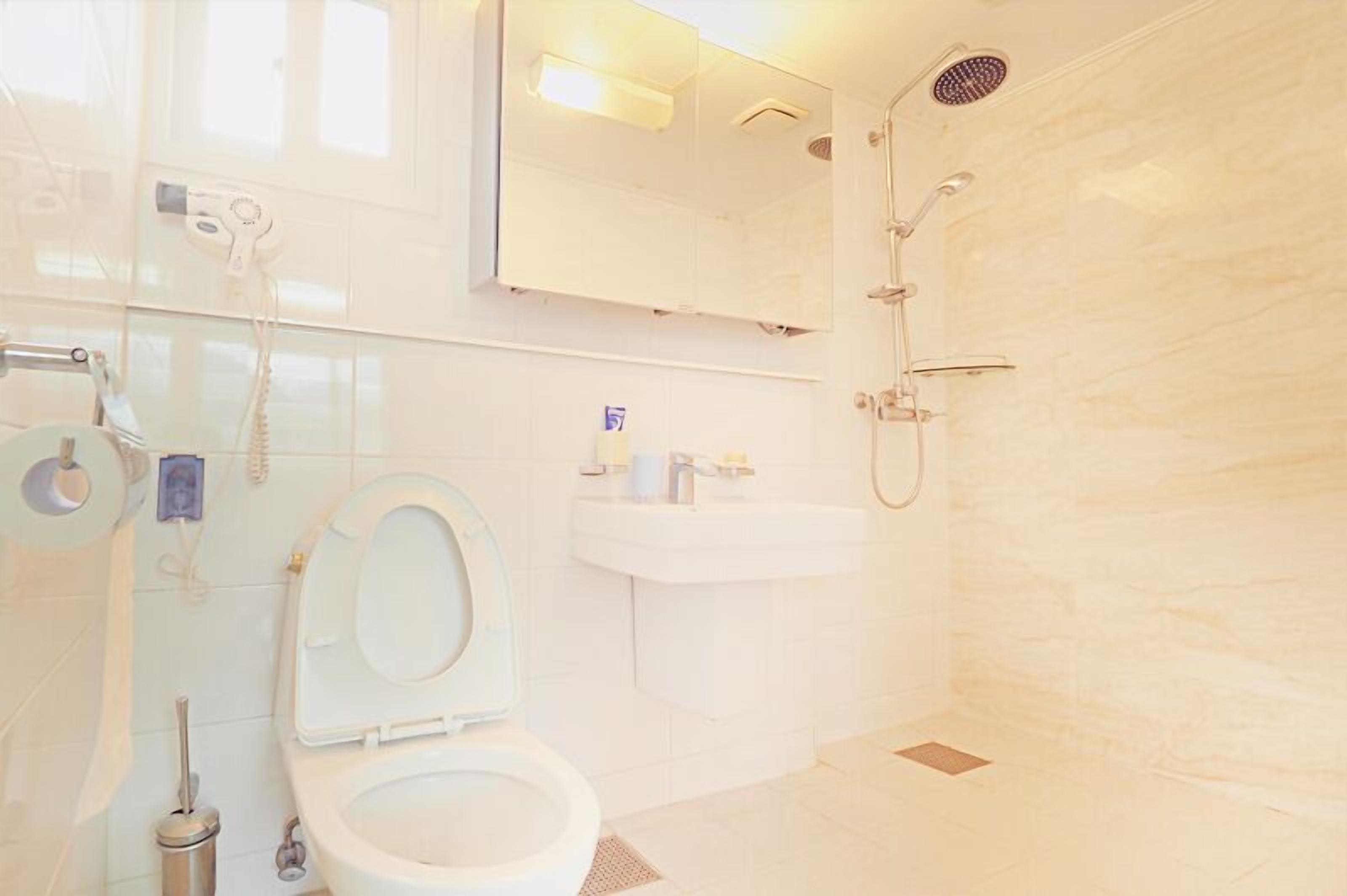 A bathroom with a toilet, sink, and shower.