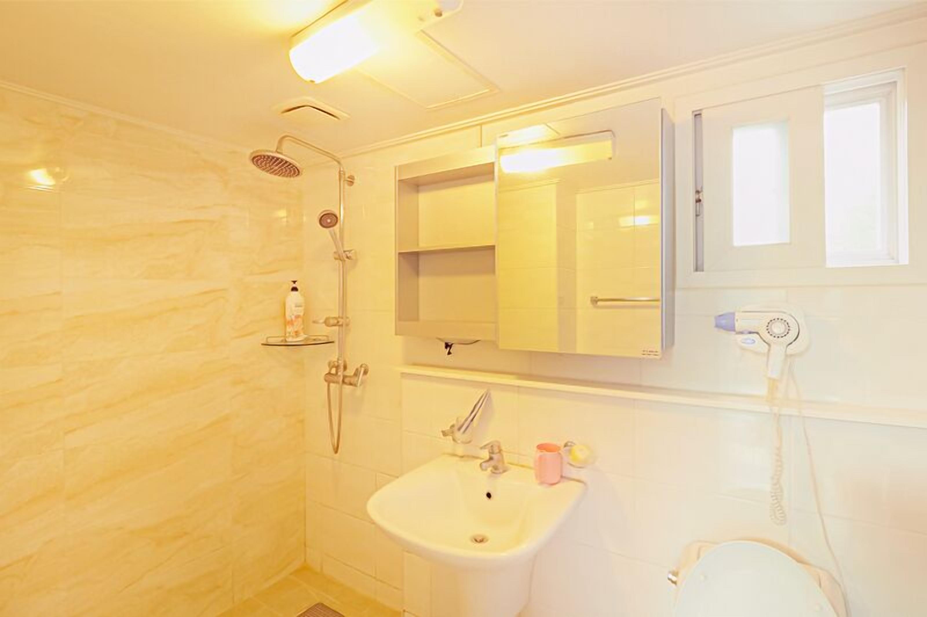 Un baño con ducha, lavabo y espejo.