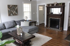 Relax in this cozy living space with a fireplace, comfortable sofa, and large window.