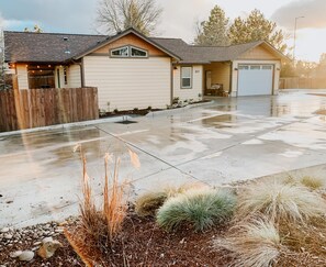 A single-story house with a garage, a driveway, and a front yard with various plants. - Home with gated driveway near River & Downtown (Grants Pass)