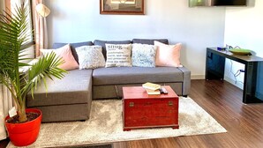 A living room with a grey sofa, a red chest of drawers, a potted plant, and a framed map on the wall.
