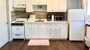 A kitchen with white cabinets, a stove, a microwave, and a refrigerator.