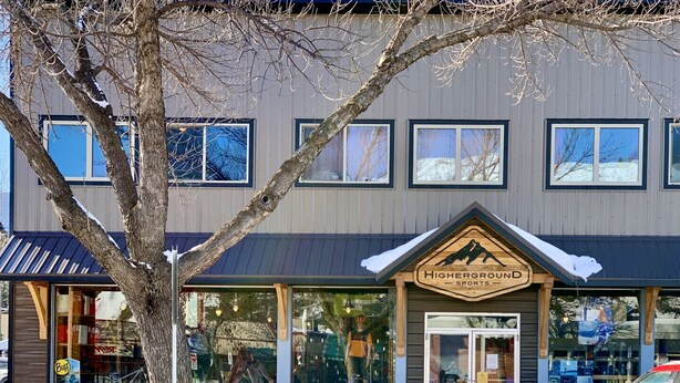 A building with a sign reading "Highground Sports" and a large window displaying a person in a yellow shirt.