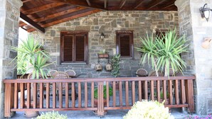 A stone building with a wooden balcony, potted plants, and wicker furniture. - Hotel Kaceli (Berat)