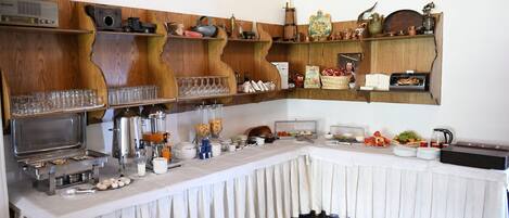 A buffet setup with various food items, utensils, and glassware.