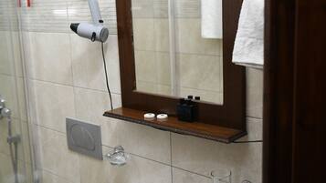 A bathroom with a white sink, a mirror, and a hairdryer mounted on the wall.