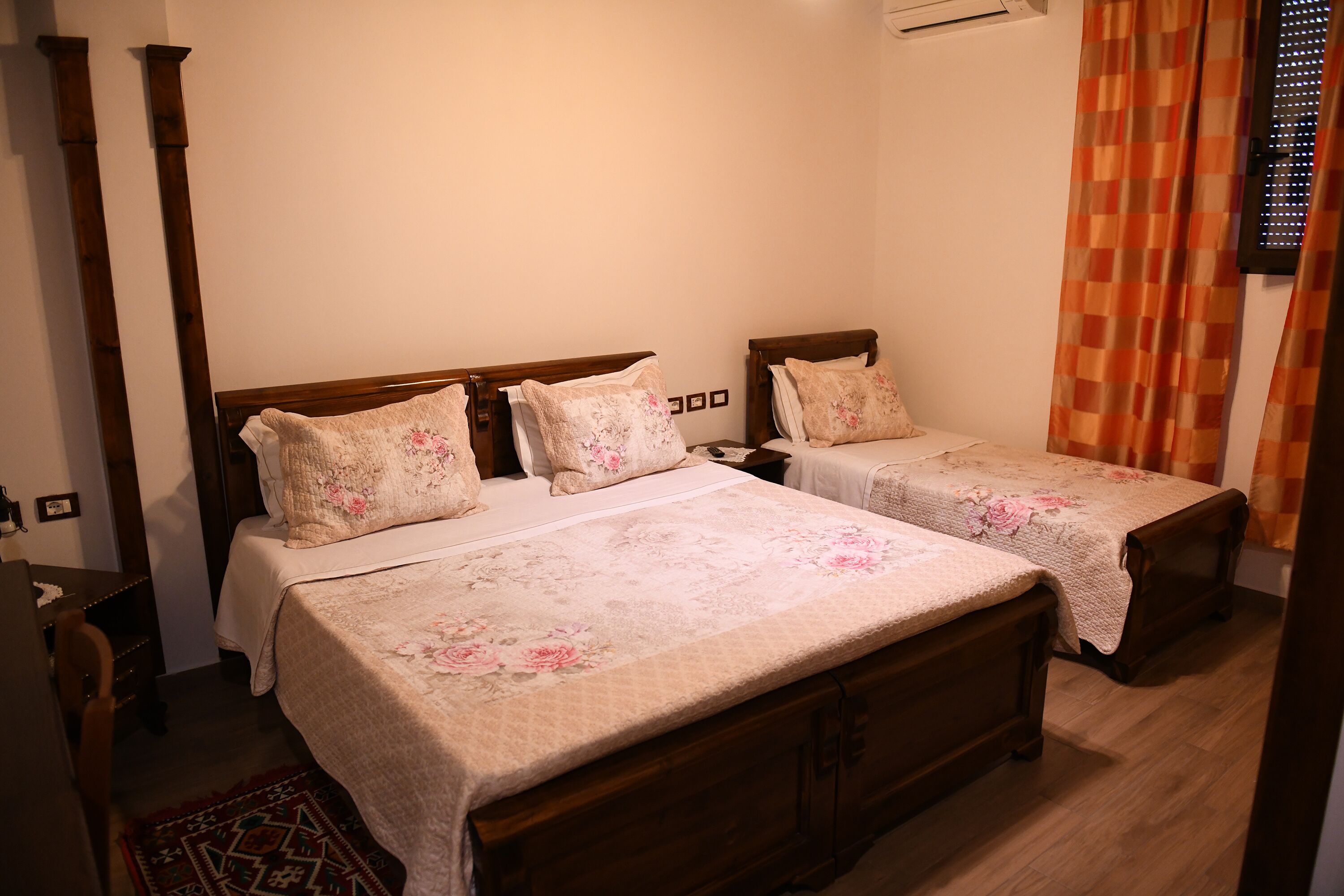 A bedroom with two single beds, wooden headboards, floral bedding, and a wooden dresser.