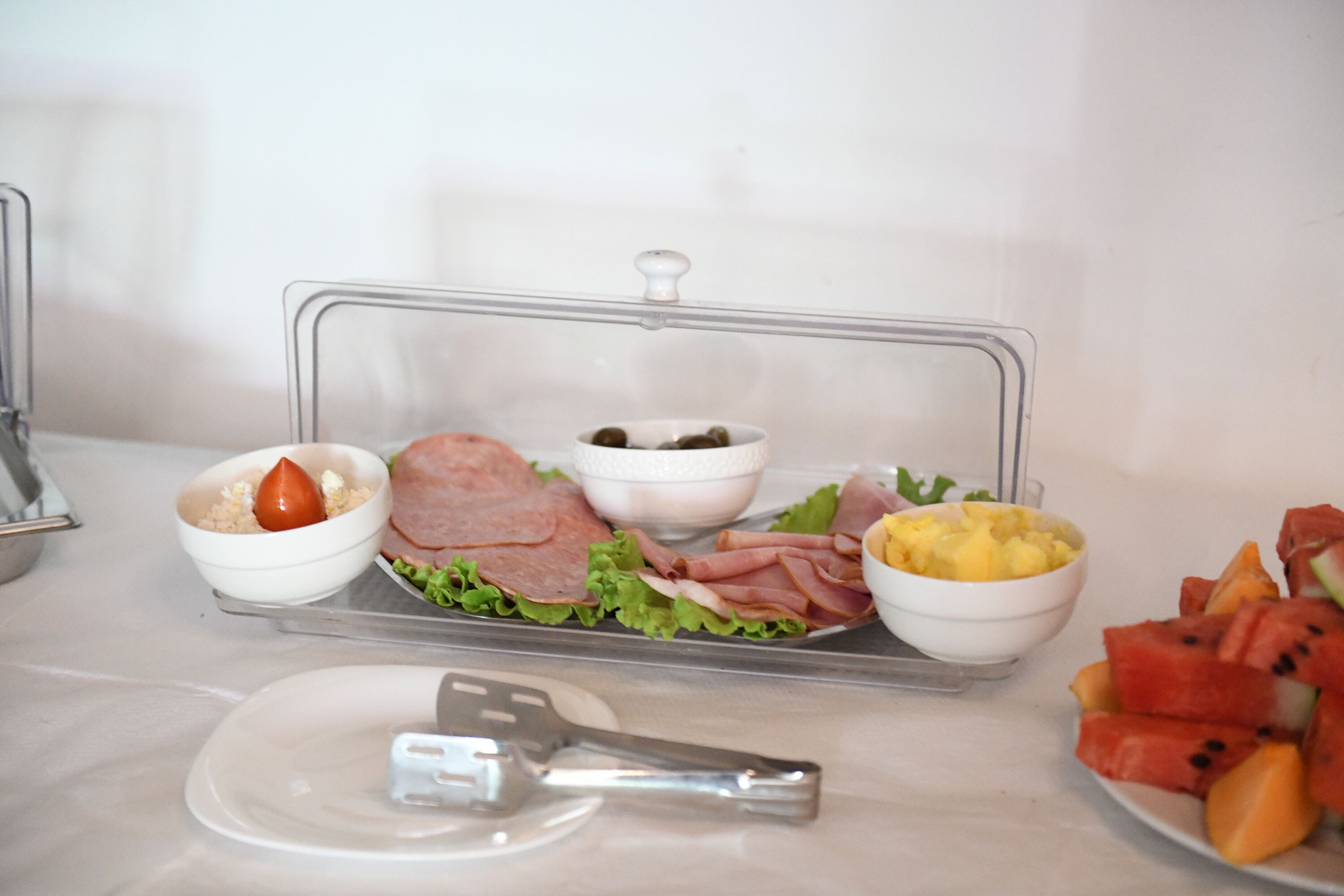 Een buffet met verschillende soorten eten, zoals ham, sla en fruit.