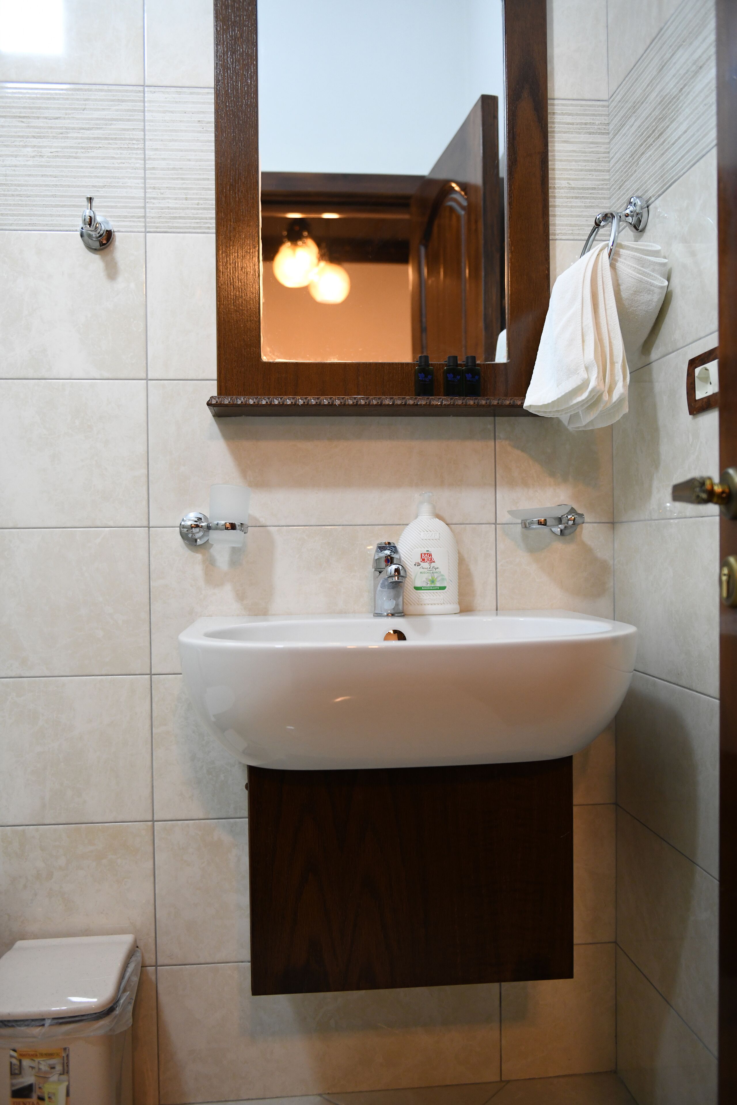 A bathroom with a white sink, a mirror, a towel rack, and a toilet.