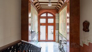 A hallway with a staircase leading to a door with barred windows. - MODERNIST FAMILY APARTMENT by PriorityVillas (Barcelona)