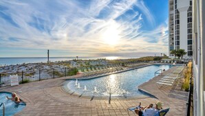 A pool area with a view of the ocean, a building with balconies, and a clear sky. - ⛱️Pelican Beach 1915 - Cloud Nine | Gulf Views | 3 Pools⛱️ (Destin)