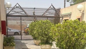 A paved courtyard with potted plants and a gated entrance.