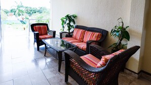 A patio area with wicker furniture, including a sofa and chairs, and a glass-top table. - Capital O Hotel Los Caracoles, Acapulco (Acapulco)