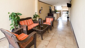 A corridor with wicker furniture, a ceiling fan, and a television mounted on the wall. - Capital O Hotel Los Caracoles, Acapulco (Acapulco)