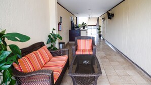 A corridor with wicker furniture, potted plants, and a fire extinguisher on the wall. - Capital O Hotel Los Caracoles, Acapulco (Acapulco)