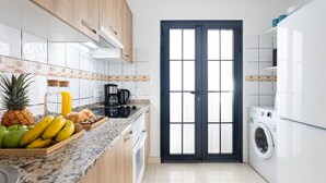 A modern kitchen with a central island, a washing machine, and a door with glass panels. - TEBAR BEACH in Playa Blanca (Playa Blanca)