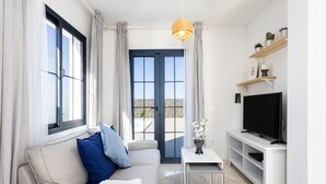 A modern living room with a sofa, TV stand, and a view through a glass door. - TEBAR BEACH in Playa Blanca (Playa Blanca)