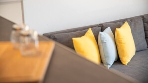 A grey sofa with three pillows in yellow, light blue, and yellow. - Costa Preciosa - Seaview apartment (Costa Adeje)
