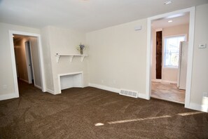 Cozy living area with a fireplace, carpeted floor, and large window.