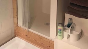 A bathroom with a shower, a sink, and a toilet. There is a bottle of shampoo and a bottle of lotion on the sink. - Van Glamping - AC, Heat and Power! (Landrum)