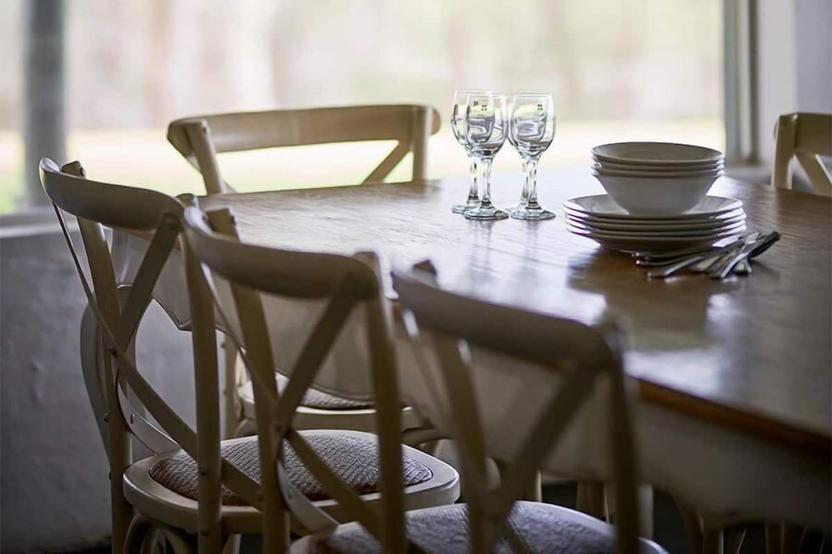 A dining table with chairs, a stack of plates, and two glasses.