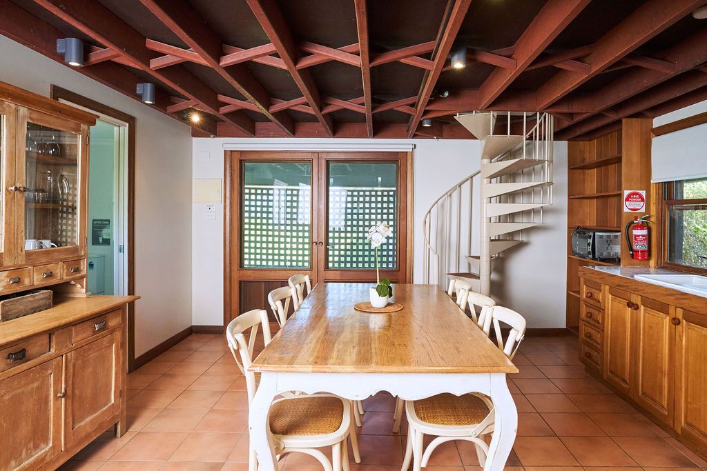 Une cuisine spacieuse avec une table en bois, des chaises blanches et un escalier en colimaçon.