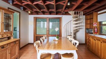 A spacious kitchen with a wooden table, white chairs, and a spiral staircase.