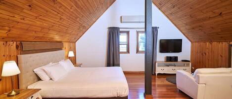 A bedroom with a large bed, a TV, and a sofa.