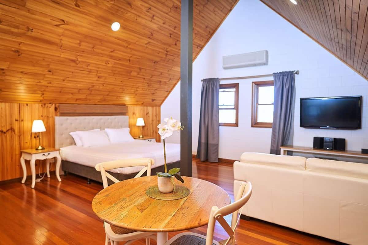 A cozy room with a bed, a sofa, a TV, and a dining table.