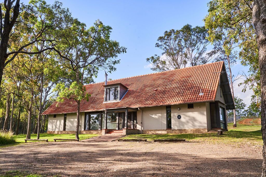 A two-story building with a red-tiled roof, large windows, and a front porch.
