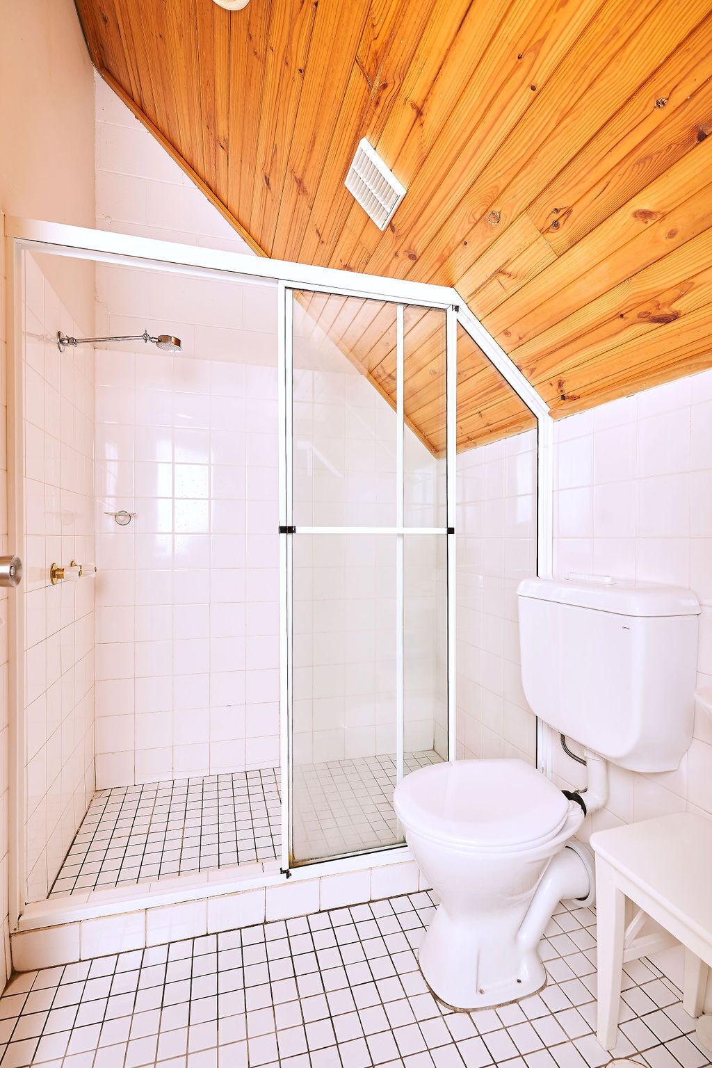 A bathroom with a shower, toilet, and tiled floor.