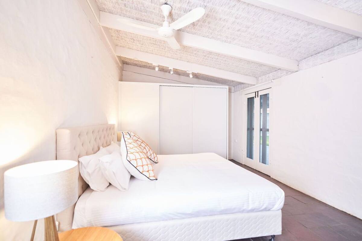 A bedroom with a bed, a ceiling fan, and a window.