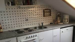 A kitchen with white cabinets, a stove, a sink, and a coffee maker. - Large vacation apartment / fitter's apartment on the outskirts of the village in a quiet location (Hochstadt am Main)
