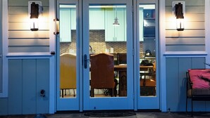 A front door with a glass panel, a dining area with a table and chairs, and a kitchen visible through the glass.
