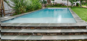 Una piscina rectangular con borde de piedra y escalones que la conducen.