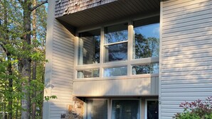 Un bâtiment à deux étages, doté de fondations en pierre, d’un balcon et d’un banc à l’extérieur.