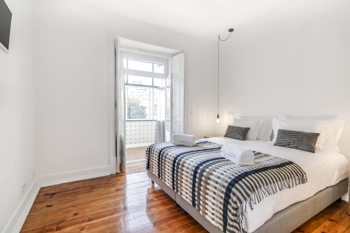 Ein Schlafzimmer mit einem großen Bett, einem Fenster und einer Tür zu einem Balkon.