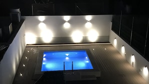 A rectangular pool with a blue water feature, surrounded by a white wall with evenly spaced lights. - Saldanha Pool & Garden (Lisbon)