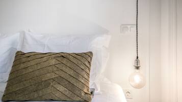 Una cama con un almohadón texturizado y una lámpara colgante.