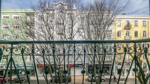 A view of a street with buildings, a fence, and a few cars. - Saldanha Pool & Garden (Lisbon)