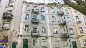 A multi-story building with patterned facades, green doors, and balconies with plants. - Saldanha Pool & Garden (Lisbon)