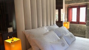 Un letto con cuscini bianchi e una lampada per lato.