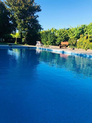 A clear blue swimming pool with lounge chairs and a wooden bench. - Quinta de Maderne (Felgueiras)