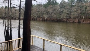 A wooden deck with a railing overlooking a calm body of water, surrounded by trees. - Relax, Fish, Visit Historic Jefferson & Caddo Lake (Jefferson)