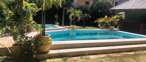 A swimming pool surrounded by potted plants and a grassy area.