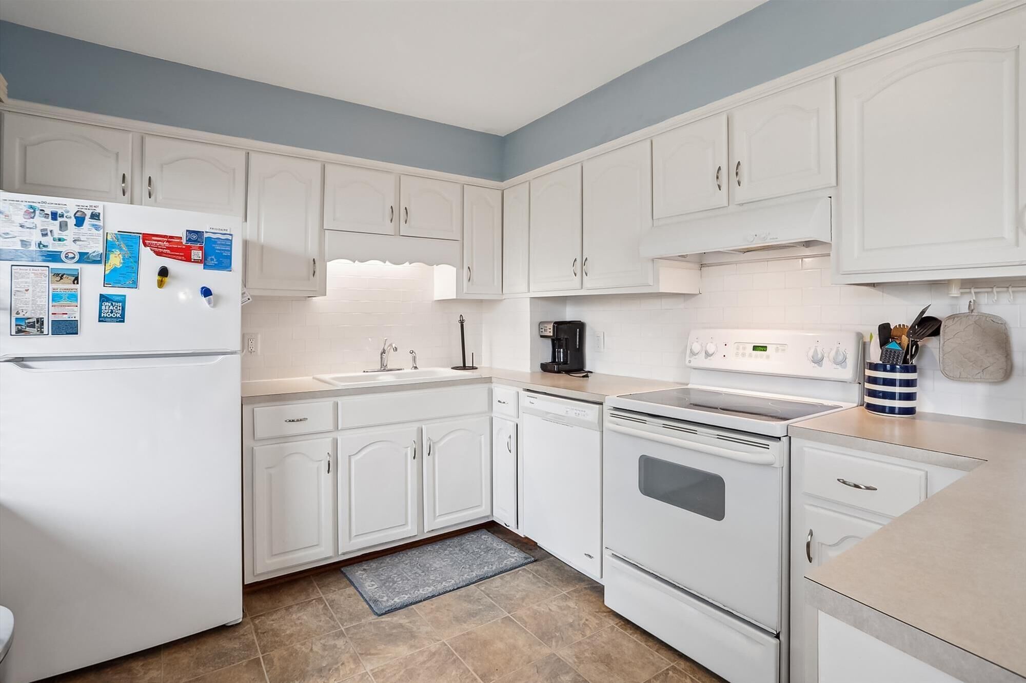 A modern kitchen with white cabinets, a built-in oven, and a coffee maker.
