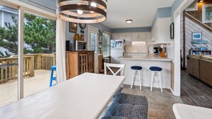 Una cocina moderna con cubierta de madera, taburetes de bar blancos y un amplio ventanal con vistas a la vegetación.